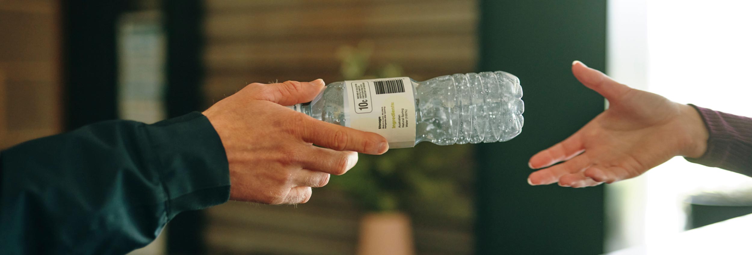 person handing plastic bottle to another person